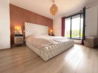 Experience modern comfort in this beautifully appointed bedroom, featuring a plush, tufted bed and a striking terracotta accent wall.