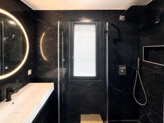 Experience modern luxury in this stunning bathroom featuring sleek black marble walls and a floating white vanity.