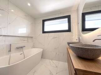 Experience modern luxury in this stunning bathroom featuring a freestanding bathtub and a sleek double vanity with vessel sinks.