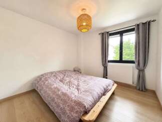 This cozy bedroom features a minimalist wooden bed frame adorned with a patterned duvet, creating a serene sleeping space.