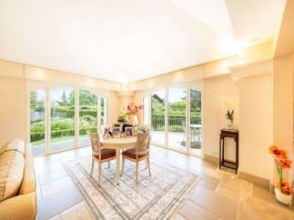Experience elegant indoor-outdoor living in this beautifully appointed dining area, featuring a charming round table with seating for four and large French doors that open to a lush garden view.
