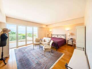 Experience luxurious living in this spacious bedroom featuring a king-sized bed with a decorative metal frame, draped in a rich plum comforter.