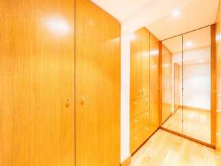 Step into this spacious walk-in closet, featuring beautiful light wood cabinetry that offers ample storage.