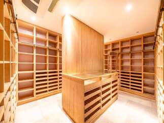 Step into this expansive walk-in closet, featuring custom-built wooden shelving and drawers for organized storage.