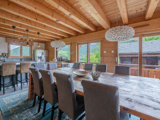 Experience rustic charm and modern comfort in this spacious dining area, featuring a large wooden table perfect for gatherings.
