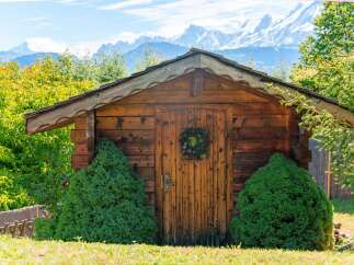 Charming wooden cabin nestled amidst lush greenery, offering a serene mountain retreat.
