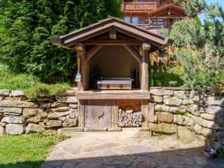 Experience outdoor living at its finest with this charming rustic outdoor kitchen, complete with a built-in grill and ample storage for firewood.