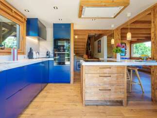 Experience luxury mountain living in this stunning kitchen featuring vibrant blue cabinetry and a rustic wooden island.