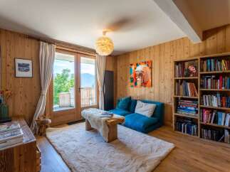Experience cozy mountain living in this charming living room, featuring warm wood-paneled walls and a plush, inviting rug.