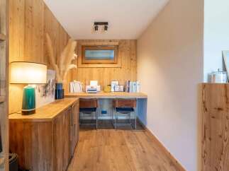 This cozy home office features a rustic wooden desk with a printer, photo frames, and a collection of books, creating a functional and inviting workspace.