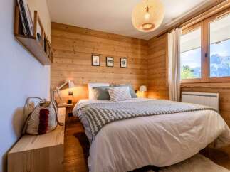 Experience cozy mountain living in this charming bedroom, featuring warm wood paneling and a comfortable queen-sized bed adorned with a stylish throw.