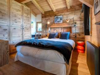 Experience rustic charm in this cozy bedroom, featuring a luxurious bed adorned with plush navy pillows and a soft duvet.