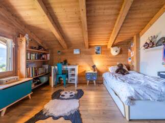 This charming attic bedroom features a cozy wooden interior with exposed beams, creating a warm and inviting atmosphere.