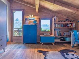 This charming attic room offers a cozy retreat with stunning mountain views visible through large windows and a balcony door.