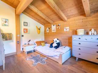 Discover this charming children's bedroom featuring a cozy bed, a playful tiger rug, and a large panda plush toy.