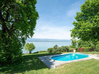 Experience serene lakeside living with this stunning property featuring a private swimming pool and lush green surroundings.