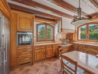 This charming kitchen features beautiful custom wooden cabinetry and exposed wooden beams on the ceiling, adding a rustic touch.