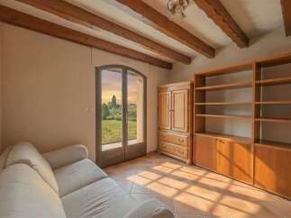 Experience rustic charm in this inviting room featuring exposed wooden beams and a large glass door offering picturesque views of the outdoors.