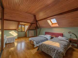 Discover this charming attic bedroom featuring two comfortable beds, perfect for families or guests.