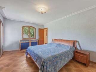 This charming bedroom features a spacious wooden bed adorned with a blue patterned comforter, complemented by a matching bedside table.