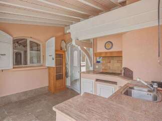 Discover this charming kitchen featuring a rustic wooden cabinet and a unique arched window with white shutters.