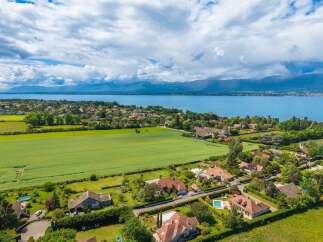 Discover this stunning aerial view of a picturesque lakeside community, showcasing beautiful homes nestled amidst lush greenery and vibrant fields.