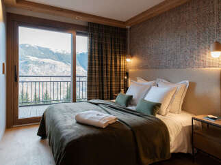 Experience breathtaking mountain views from this luxurious bedroom, featuring a comfortable king-size bed and a private balcony.