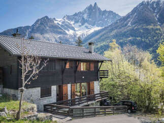 Experience the charm of this traditional wooden chalet nestled against a breathtaking mountain backdrop.
