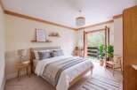 Experience serene living in this beautifully appointed bedroom, featuring a comfortable queen-size bed with plush grey linens and a cozy striped throw.