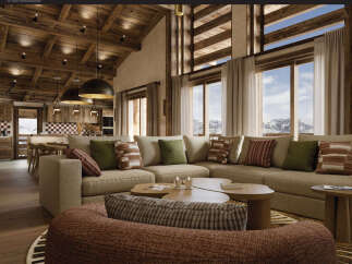 Experience luxury mountain living in this stunning chalet-style living room, featuring a spacious sectional sofa and large windows with breathtaking mountain views.