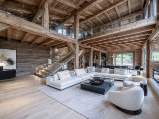Experience luxury mountain living in this stunning chalet featuring a grand open-concept living area with soaring wooden beams and a modern fireplace.