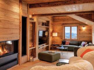 Experience cozy luxury in this stunning mountain chalet living room, featuring a modern fireplace and a plush sectional sofa perfect for relaxing.