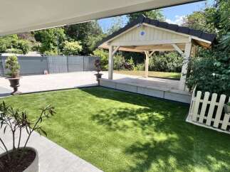 Discover this stunning property featuring a modern outdoor living space with artificial turf and a charming gazebo.