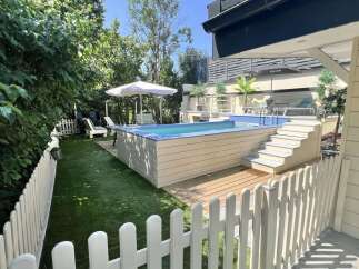 Escape to this backyard oasis featuring a modern above-ground pool with a sleek wooden deck and integrated steps.