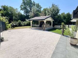 Discover this charming property featuring a covered carport perfect for sheltering vehicles, surrounded by lush greenery and mature trees.