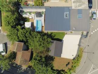 Discover this stunning property featuring a modern home with a sleek metal roof and skylights, complemented by a luxurious swimming pool and expansive wooden deck.