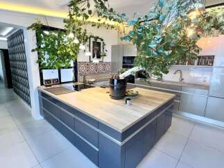 Experience modern living in this stunning kitchen featuring a sleek island with a light wood countertop, perfect for meal prep and casual dining.