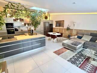 Experience modern living in this open-concept space, featuring a sleek grey kitchen island with a built-in stovetop and a spacious living area with a comfortable sectional sofa.
