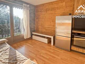 Experience cozy living in this charming studio apartment, featuring a comfortable bed, a functional kitchenette with a refrigerator and oven, and a bright living area with access to a balcony.