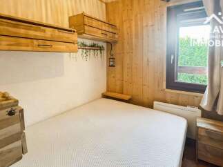 Experience cozy living in this charming bedroom featuring rustic wooden walls and a comfortable bed.