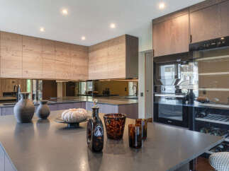 Experience luxury in this modern kitchen featuring sleek wooden cabinetry and a spacious stone island.