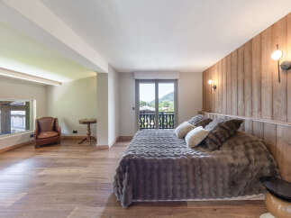 Experience luxurious mountain living in this beautifully appointed bedroom, featuring a plush king-size bed with a cozy faux fur throw and elegant wood-paneled walls.