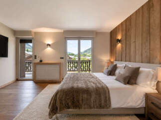 Experience luxurious mountain living in this beautifully appointed bedroom, featuring a cozy king-sized bed with plush bedding and a stunning wooden accent wall.