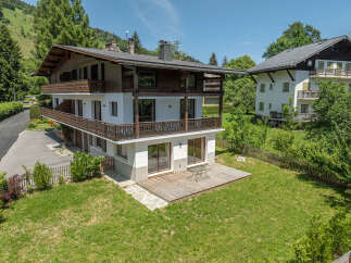 Experience alpine living in this charming multi-story home, featuring a striking wooden exterior and multiple balconies offering scenic views.