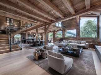 Experience luxurious mountain living in this stunning chalet featuring a grand open-plan living area with exposed wooden beams and a modern fireplace.