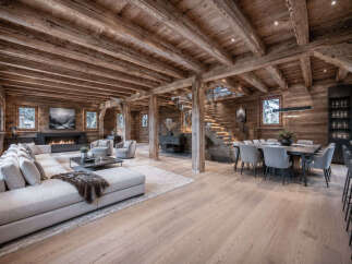 Experience luxury mountain living in this stunning timber-framed home, featuring a spacious open-concept living area with a modern fireplace and comfortable sectional sofa.