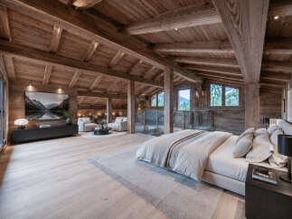 Experience luxurious mountain living in this stunning chalet bedroom, featuring a vaulted wooden beam ceiling and panoramic windows offering breathtaking views.