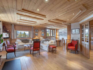 Experience luxurious alpine living in this stunning wooden chalet, featuring a spacious living area with comfortable sofas and a cozy fireplace.