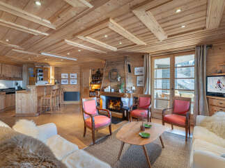 Experience the ultimate alpine retreat in this charming wooden chalet living room, featuring a cozy fireplace and a well-equipped kitchen with a breakfast bar.