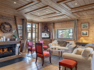 Experience cozy mountain living in this charming wooden chalet living room, featuring a crackling fireplace and comfortable seating.